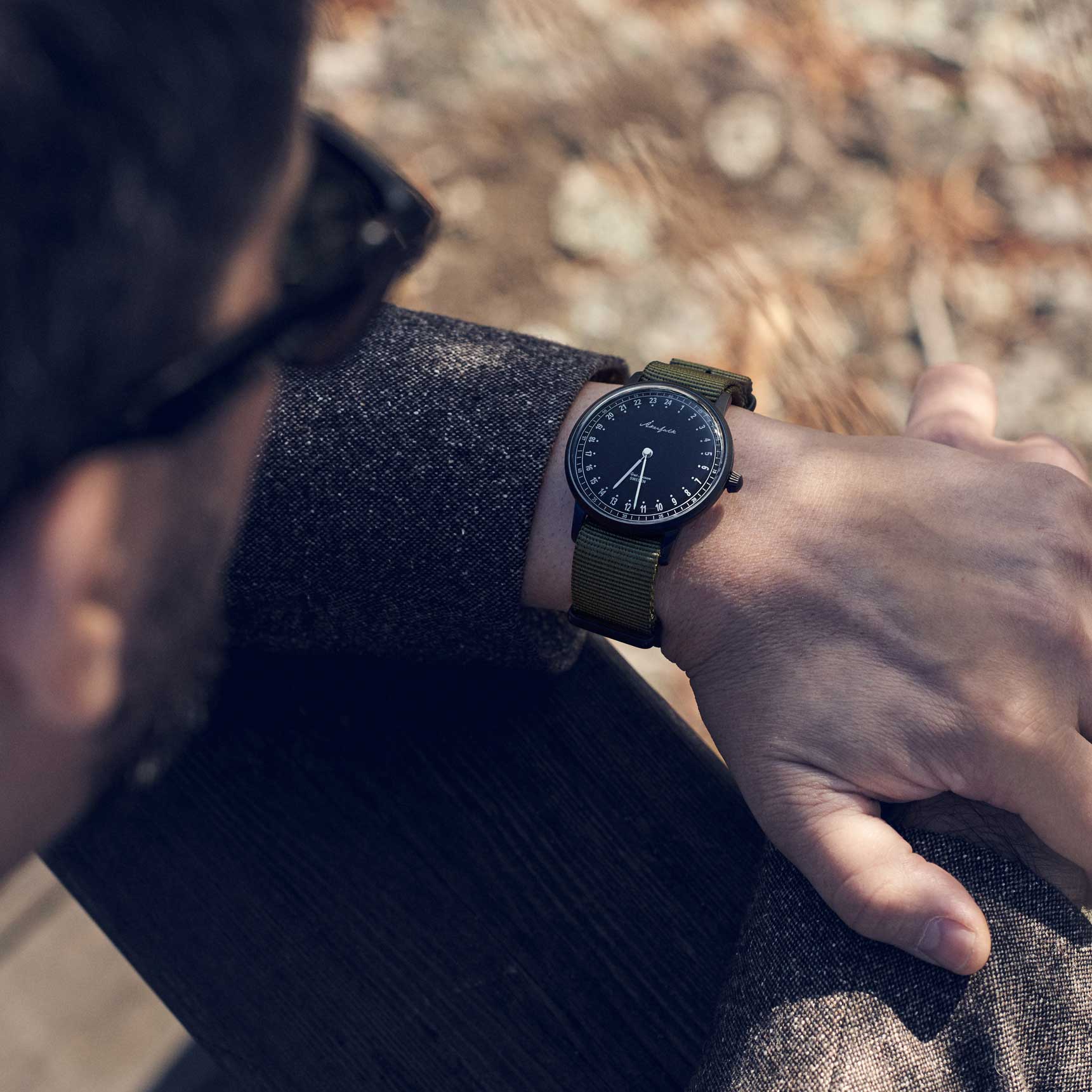 24-hour watch with matte black case and green NATO strap